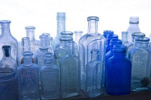 A grouping of antique glass medicine bottles sits on the window shelf of an old pharmacy.